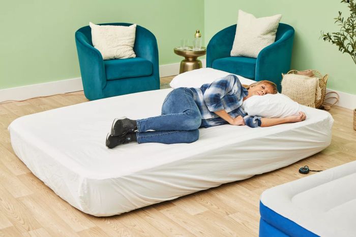 A person is lying on the Simmons Lumbar Firm Full Tri-Zone Air Mattress.