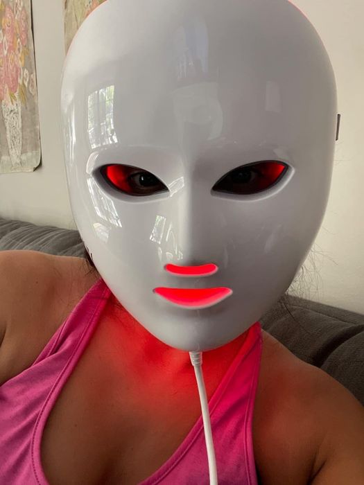 A reviewer using an LED face mask as part of their skincare routine.