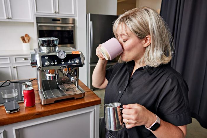 A person is sipping from a mug in front of the De'Longhi La Specialista Prestigio Espresso Machine.