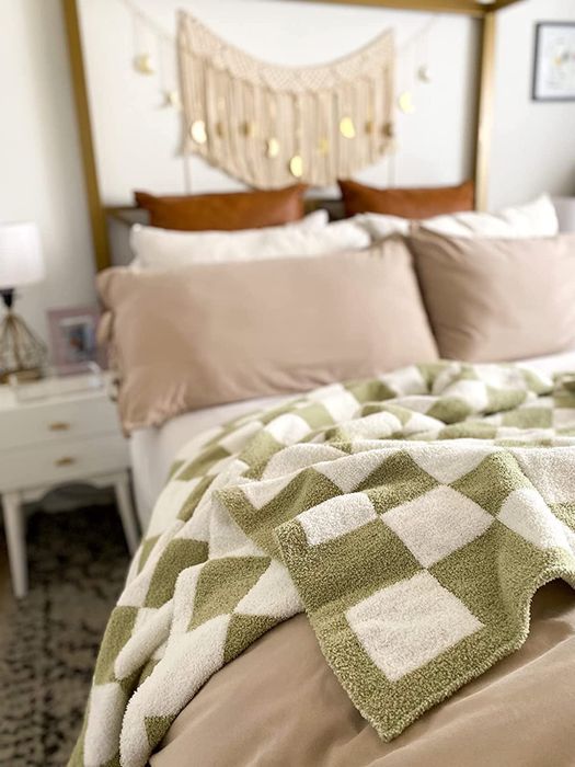 The sage green checked blanket draped over a bed.