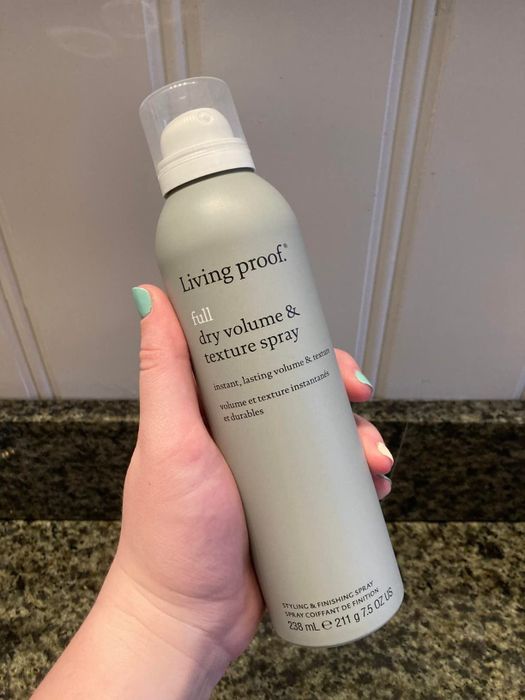 A reviewer holding a can of the product