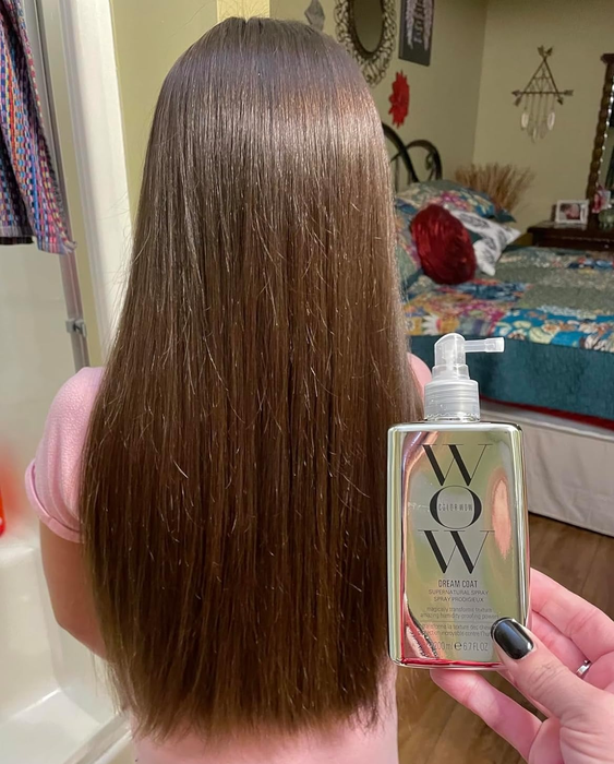A person holding a hair care product next to their long, straight hair, likely endorsing its effectiveness