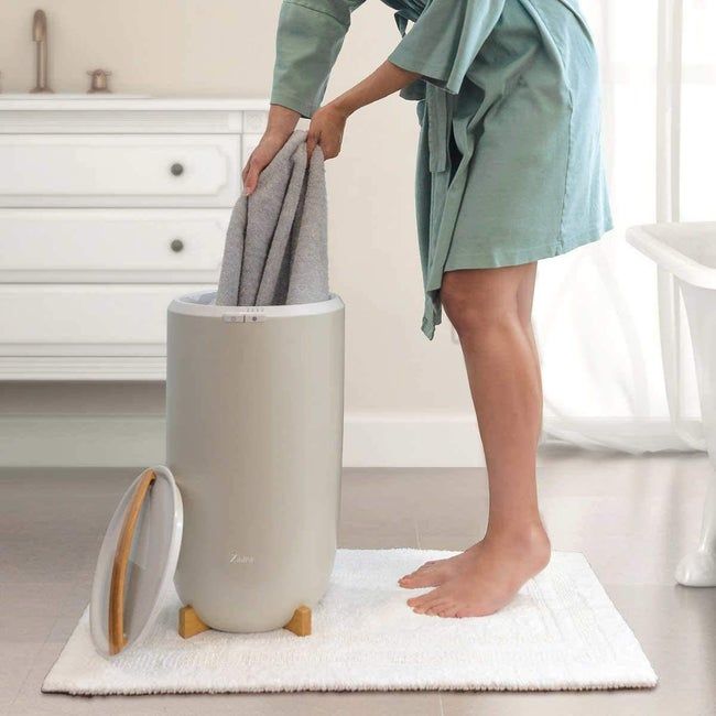 A model taking a towel out of a sleek silver towel warmer.