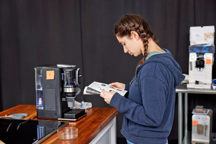 Person reading the instruction manual for a Cuisinart Single-Serve Grind and Brew