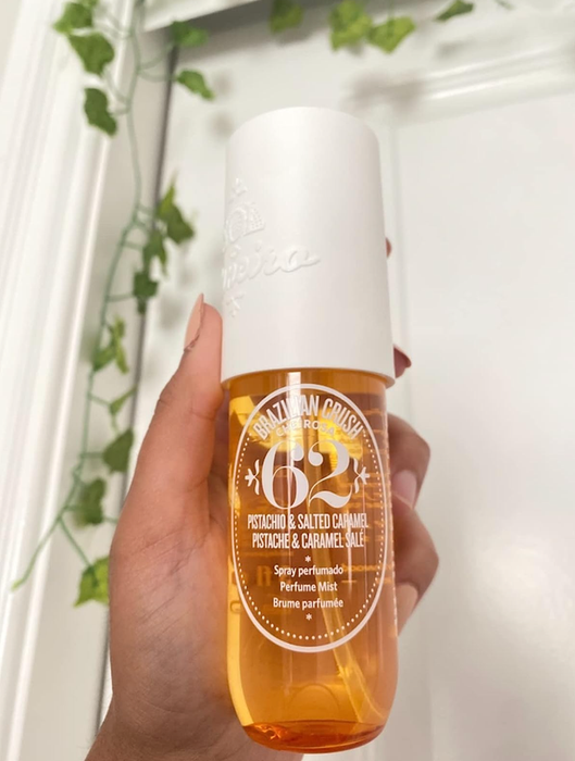 A reviewer holding a spray perfume bottle