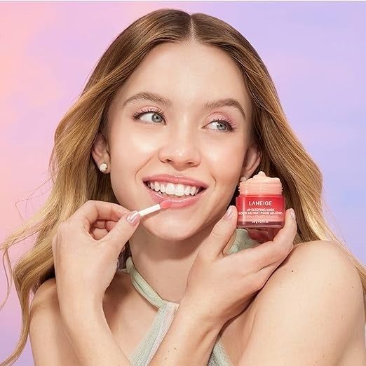 Sydney Sweeney applying lip balm, holding the product, and dressed in a simple sleeveless top