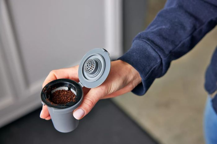 Person adding coffee grounds to a reusable coffee pod for a Cuisinart Single-Serve Grind and Brew