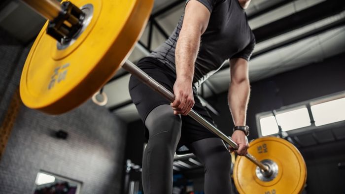 Lifting a barbell that features yellow weight plates