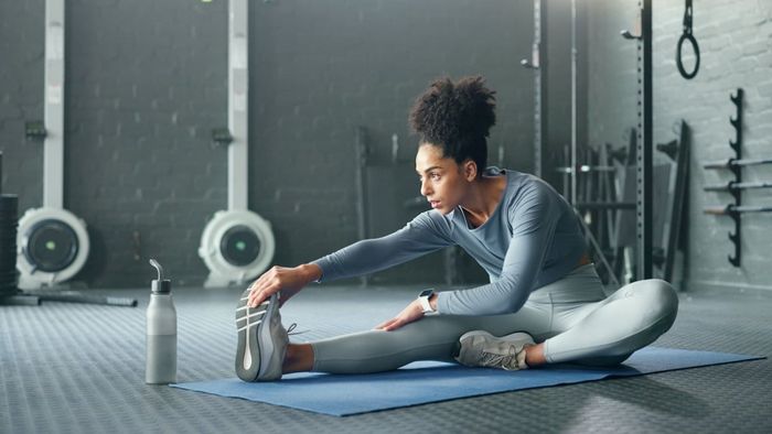 a woman performing a runner's stretch in a gym