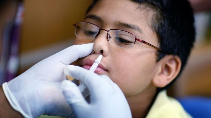 A boy receiving a flu vaccine through nasal administration