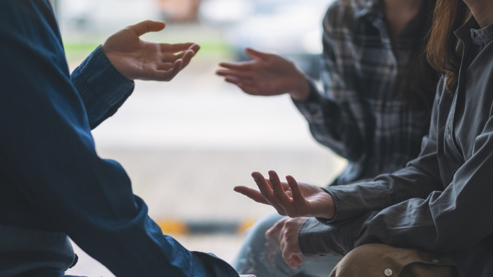 Individuals engaged in conversation, using hand gestures while talking