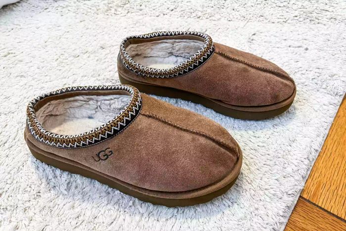 A pair of Ugg Tasman slippers resting on a pristine white carpet