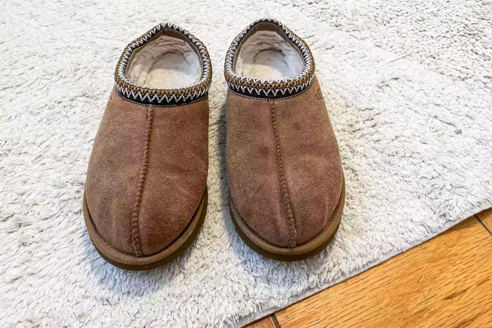 A pair of Ugg Tasman slippers laid out on a white carpet
