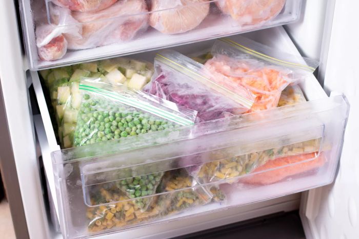 A variety of frozen vegetables stored in a household freezer. Frozen goods neatly organized in the freezer