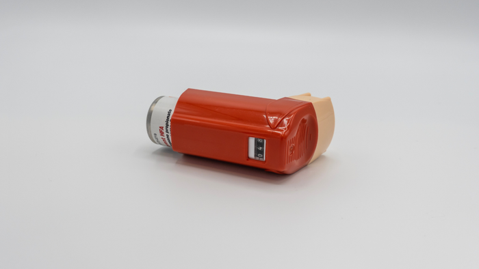 A Flovent inhaler resting on a plain white surface.