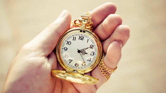 A gold pocket watch gently lying in the open hand of an individual