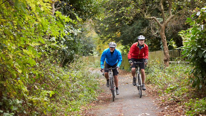 two cyclists riding on a trail in a park