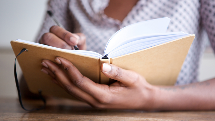A person jotting down thoughts in a journal