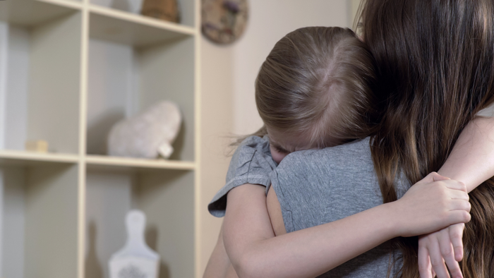 a mother embracing and consoling a distressed young girl