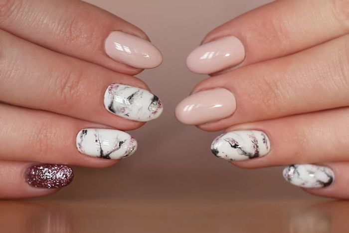 Nail manicure styles featuring marble designs, shades of white, black, and pink, all finished with a shiny look