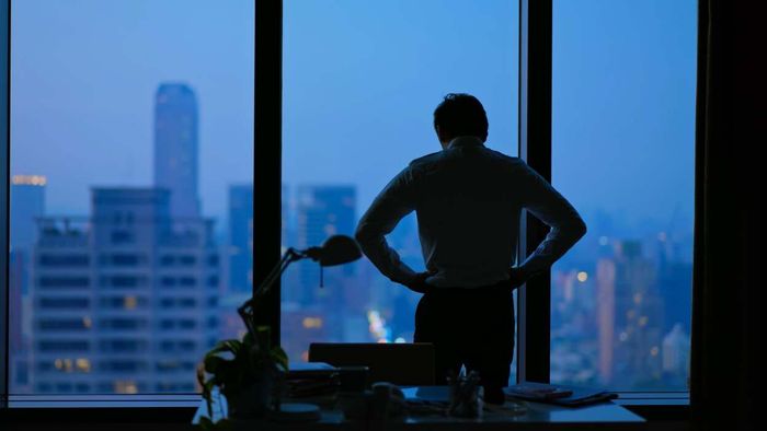 A person gazing out of an office window during twilight