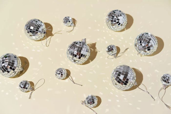 Silver disco balls on a soft beige backdrop. Wishing you a joyful New Year. A minimalist take on the holiday season.