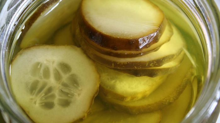A jar filled with pickle slices and the briny juice that accompanies them.