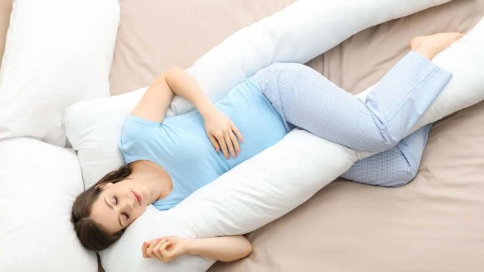 A pregnant individual enjoying rest with a pregnancy pillow