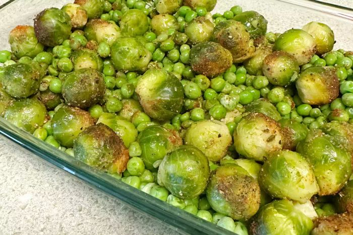 Close-up of the Pyrex Easy Grab Glass Baking Dish with Lid, filled with Brussels sprouts and green peas.