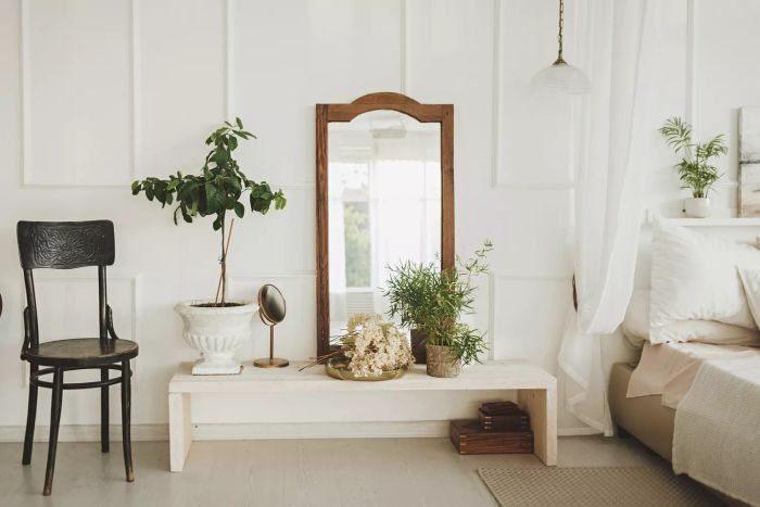 Bohemian-inspired living room decor featuring a wooden cabinet, a stylish armchair, tropical plants, and chic accessories.