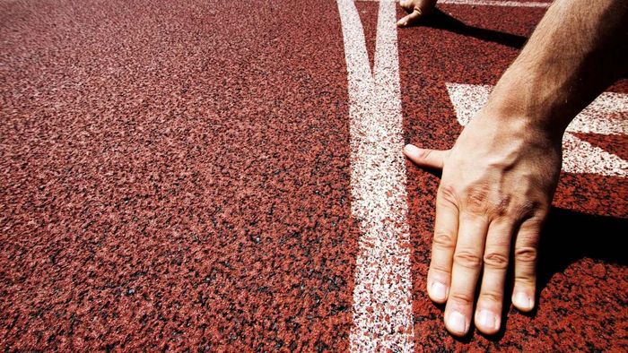 A close-up shot of a runner's hand, ready to start at the starting line