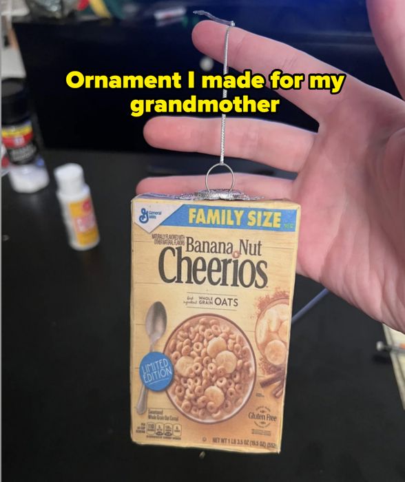 A hand holding a small, intricate model or ornament of a Banana Nut Cheerios cereal box labeled 'limited edition.'