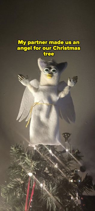 A Furby angel tree topper with wings and a halo placed atop a beautifully decorated Christmas tree.