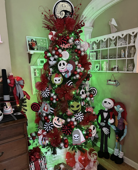 A Christmas tree adorned with 'Nightmare Before Christmas' ornaments, featuring Jack and Sally figures standing next to the tree