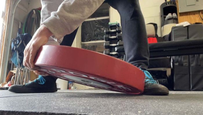 To lift a plate, place one foot against its edge and grip the opposite side with your hands before lifting.