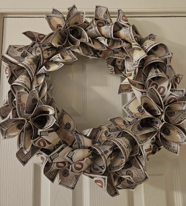 A wreath crafted from folded U.S. currency hanging on a door.