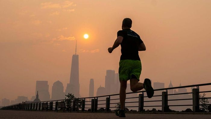 A jogger runs through Liberty State Park with the One World Trade Center and the New York skyline in the distance, as smoke from wildfires in Canada blankets the Manhattan area.