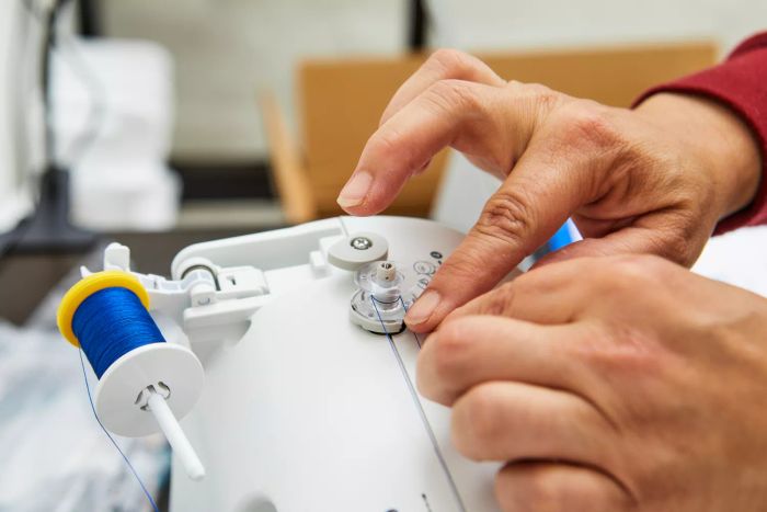 Close-up of a person winding the bobbin on the Brother XR9550 Sewing Machine.