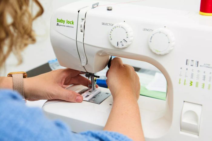 A person lowering the presser foot on the Baby Lock Zest Sewing Machine.