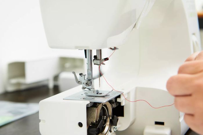 A close-up shot of a person threading the Baby Lock Zest Sewing Machine.