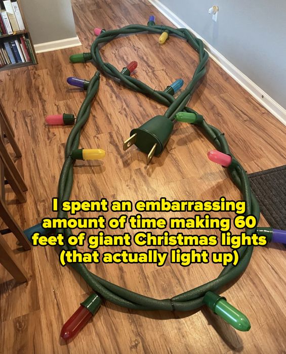 An oversized green electrical plug and cord with large, vibrant lights scattered across a wooden floor