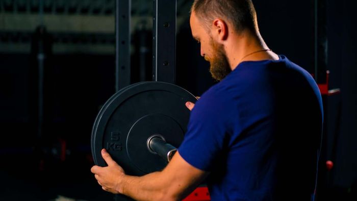 a man preparing a barbell in a gym setting