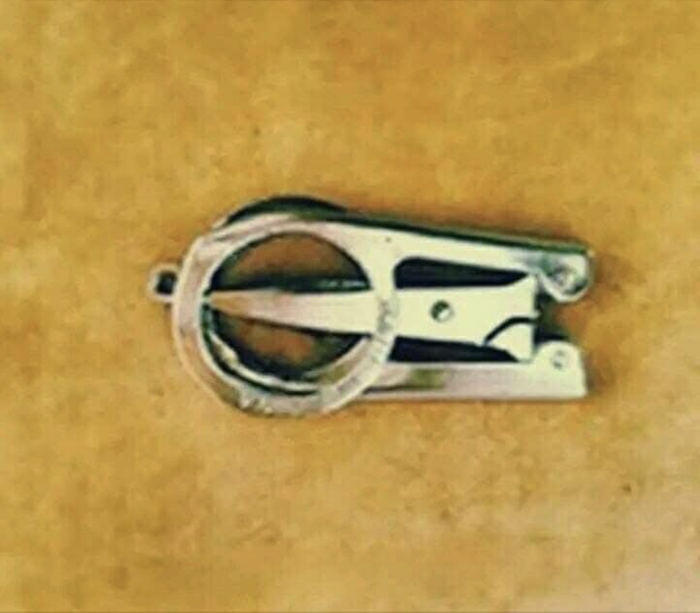 A metal staple remover resting on a flat surface, viewed from above.