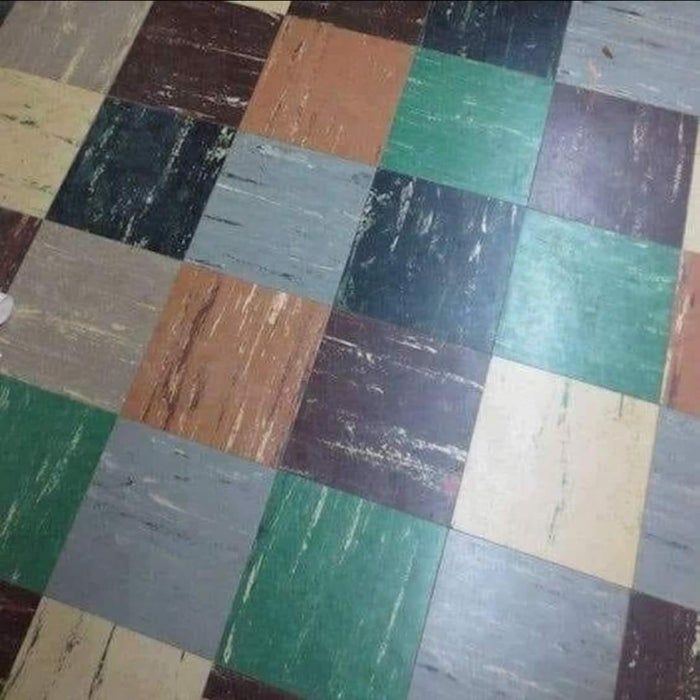 A floor with square tiles in earthy shades, showing subtle wear and texture over time