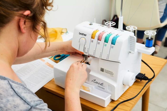 A person operating the Brother 1034D Serger Machine on a wooden surface.