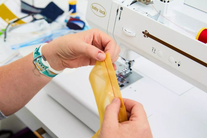 A pair of hands gently holding a delicate fabric that has been stitched in front of the Baby Lock Jazz II Sewing Machine.