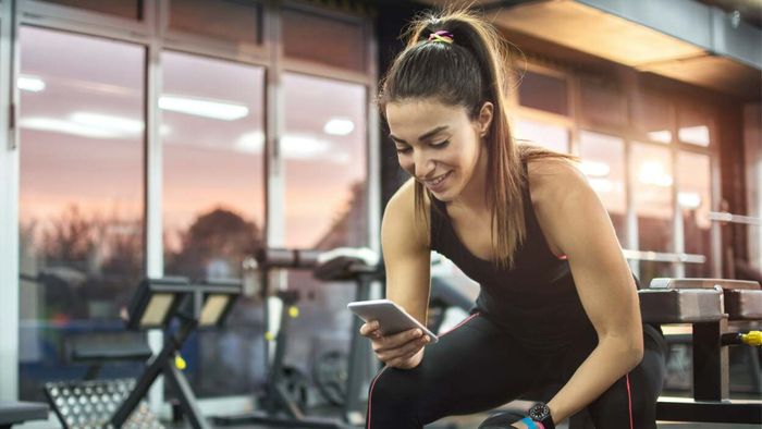 woman browsing her phone while at the gym