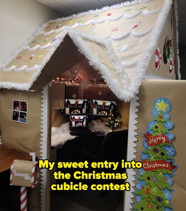 A cubicle transformed into a gingerbread house, featuring colorful wrapping paper, candy decorations, and a Christmas tree