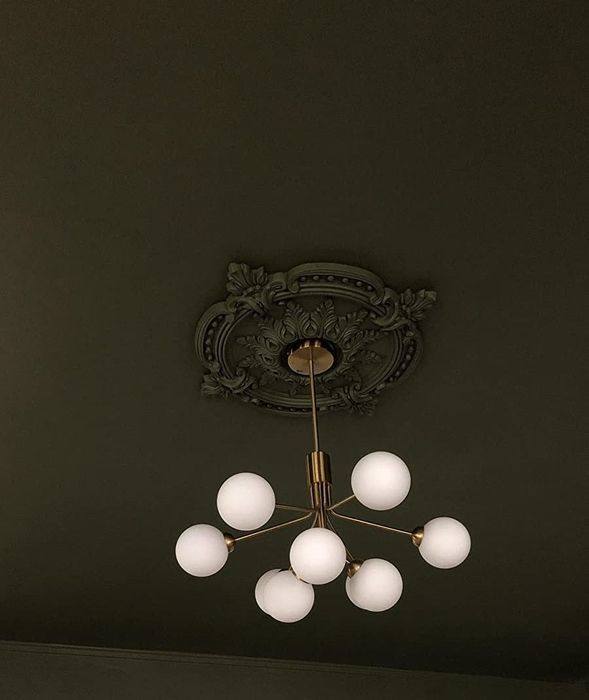 A reviewer’s image showing a dark green painted medallion installed on the ceiling, blending seamlessly with the rest of the room’s decor.