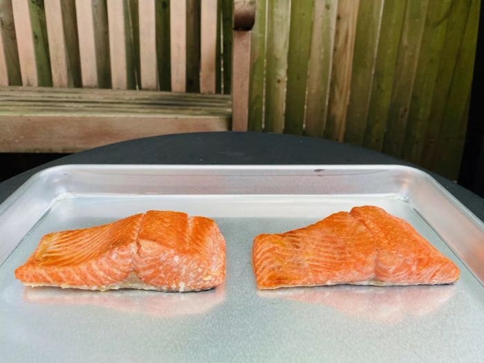Two salted salmon fillets placed on a baking sheet